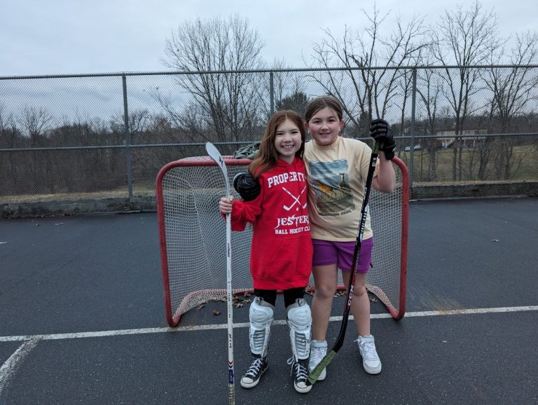 Natalie Van Druff, 11, left, and Lilly Walter, 11, right, take a break from playing pick up hockey at New Hanover Community Park to pose for a picture.